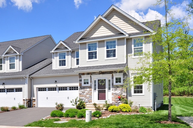 view of property with asphalt driveway, a front yard, stone siding, an attached garage, and roof with shingles
