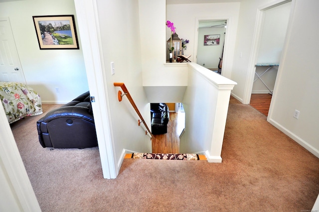 hallway featuring an upstairs landing, carpet flooring, and baseboards