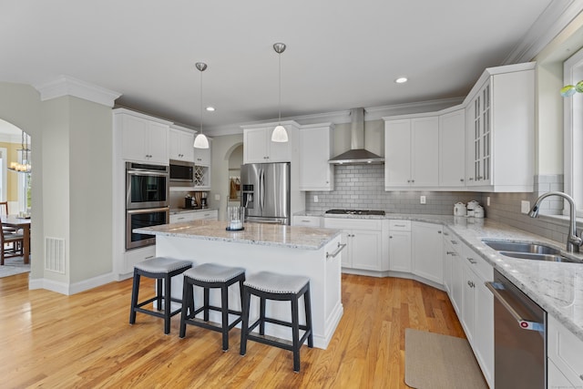 20 Peach Ln, East Lyme, CT 06333 - kitchen featuring stainless steel appliances, wall chimney range hood, a sink, arched walkways, and a breakfast bar area