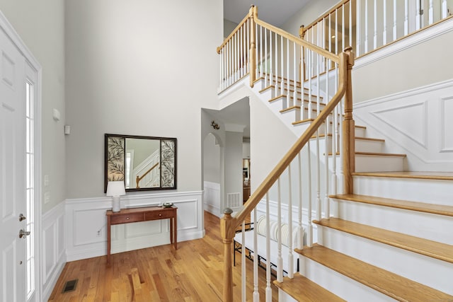 20 Peach Ln, East Lyme, CT 06333 - foyer featuring wood finished floors, stairway, a high ceiling, a wainscoted wall, and arched walkways