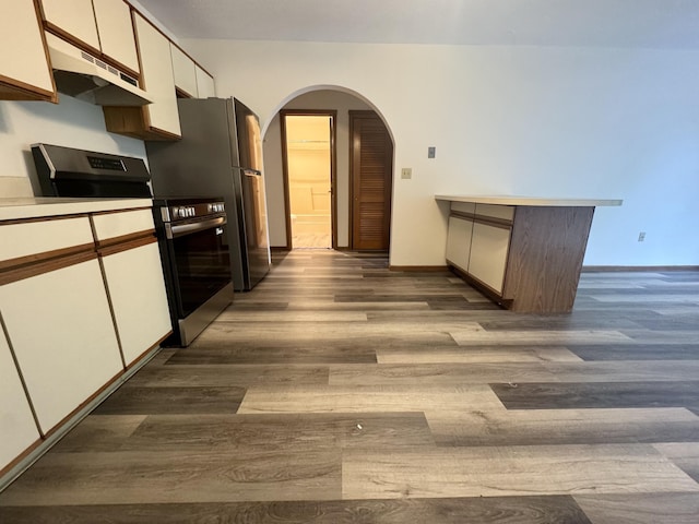 kitchen with under cabinet range hood, arched walkways, dark wood-style floors, white cabinets, and stainless steel range with electric cooktop