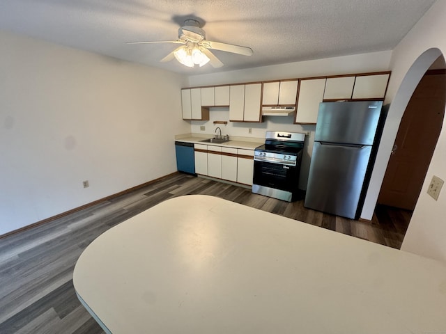 kitchen featuring a ceiling fan, a sink, stainless steel appliances, arched walkways, and under cabinet range hood
