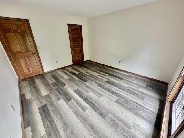 unfurnished bedroom featuring baseboards, a closet, and wood finished floors