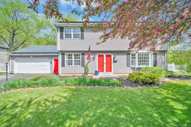 colonial inspired home featuring an attached garage, fence, solar panels, a front yard, and driveway