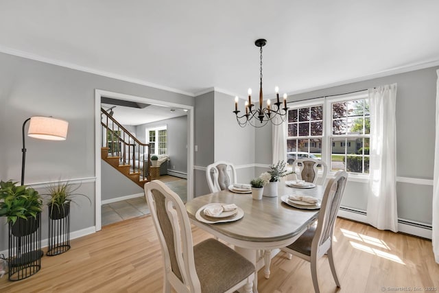 dining area with an inviting chandelier, light wood-style flooring, a baseboard heating unit, and a healthy amount of sunlight