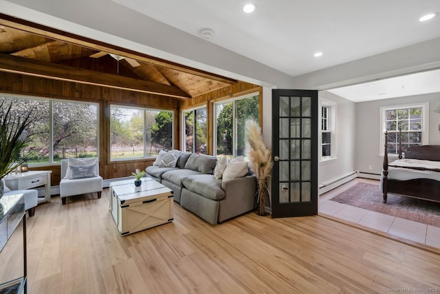 living area with a baseboard radiator, lofted ceiling, baseboard heating, and light wood-style floors