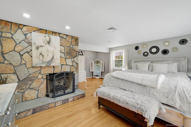 bedroom with a fireplace, recessed lighting, visible vents, and wood finished floors