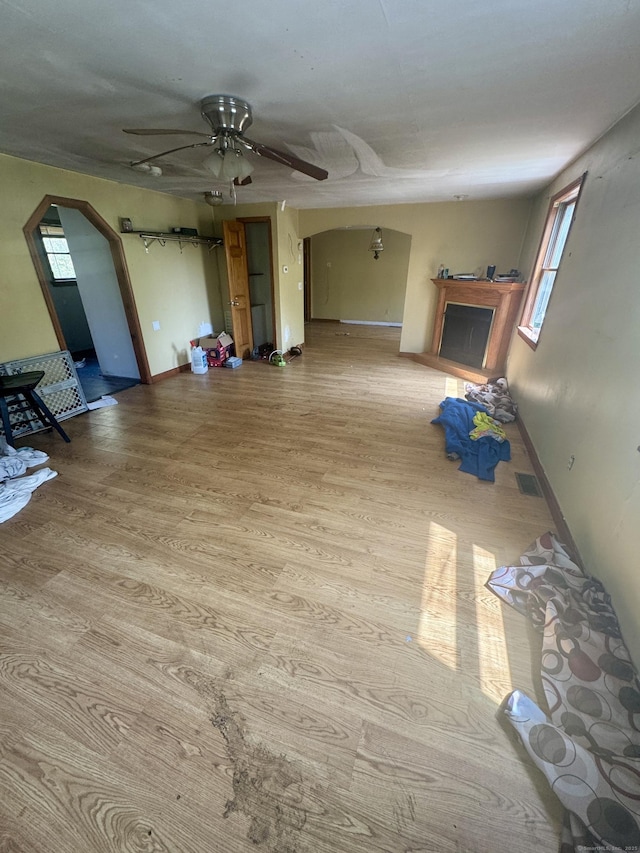 unfurnished living room featuring ceiling fan, arched walkways, a healthy amount of sunlight, and visible vents