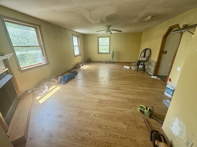 empty room with arched walkways, ceiling fan, and wood finished floors