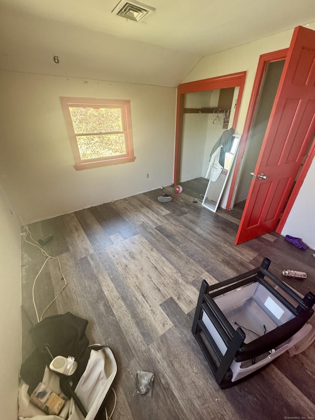 unfurnished bedroom with vaulted ceiling, visible vents, and dark wood finished floors