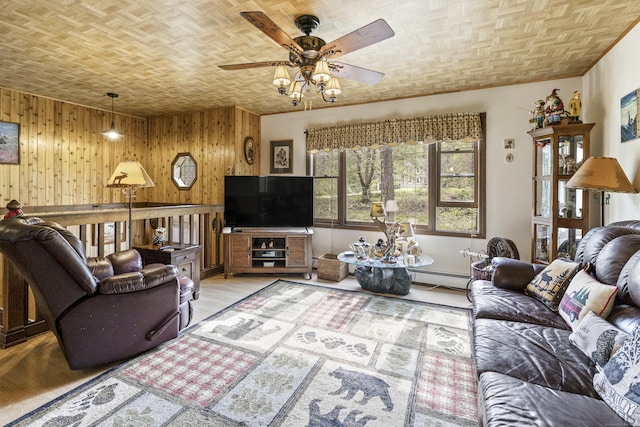 living room with wooden walls, a ceiling fan, baseboard heating, and light wood-style floors