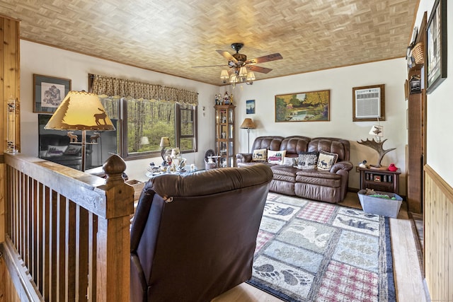 living area with a wall unit AC, ceiling fan, and wood finished floors