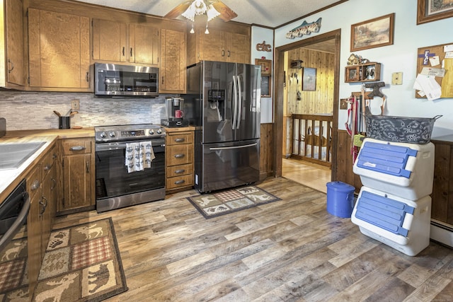 kitchen with a ceiling fan, light wood finished floors, decorative backsplash, light countertops, and appliances with stainless steel finishes