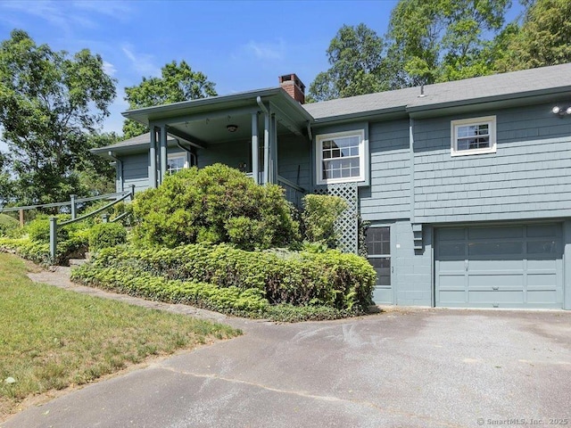 23 Pine Woods Rd, North Stonington, CT 06359 - view of front facade with an attached garage, a chimney, and asphalt driveway