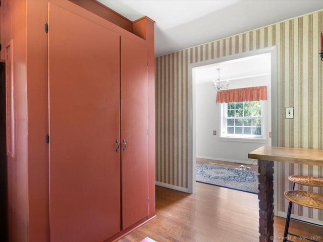 23 Pine Woods Rd, North Stonington, CT 06359 - hallway featuring wallpapered walls, light wood finished floors, and a chandelier
