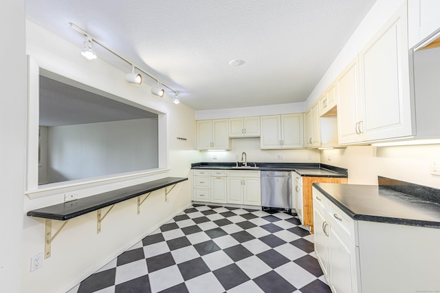 kitchen featuring dishwasher, dark flooring, dark countertops, a sink, and baseboards