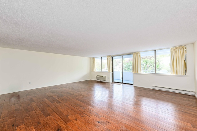 unfurnished living room with a baseboard heating unit, a wall mounted air conditioner, hardwood / wood-style floors, and a textured ceiling