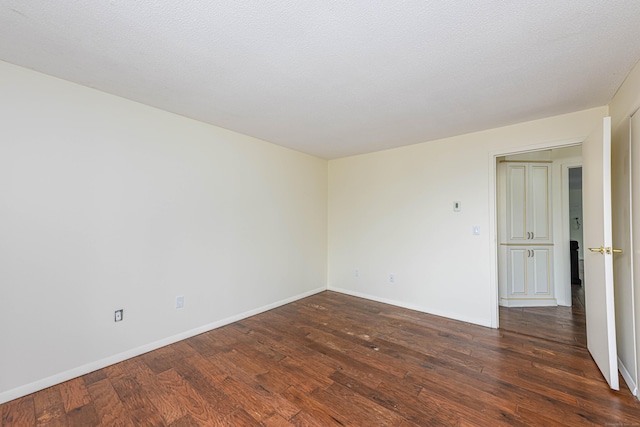 unfurnished room with dark wood-style flooring and baseboards