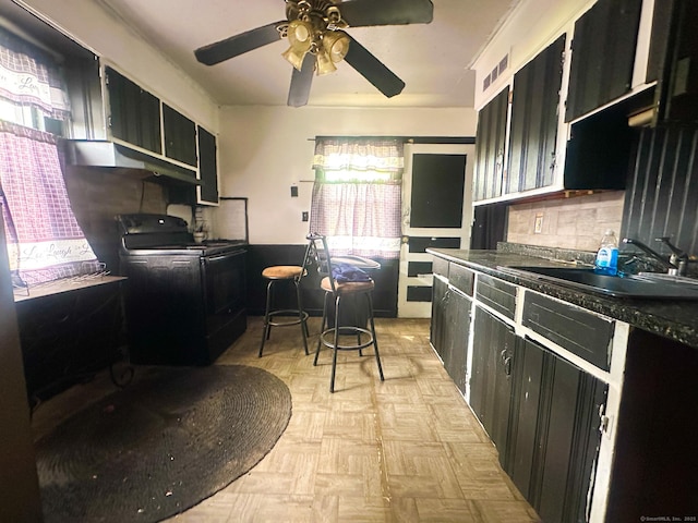 kitchen with black range with electric stovetop, a sink, and dark cabinets
