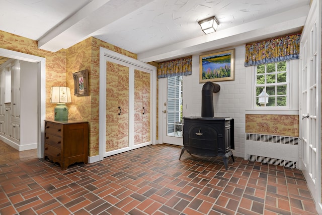 173 Highwoods Dr, Guilford, CT 06437 - interior space with radiator heating unit, brick floors, wallpapered walls, a wood stove, and baseboards