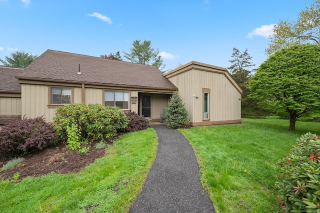 view of front of home with a shingled roof and a front yard