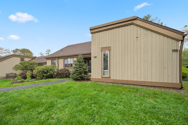 rear view of property featuring a lawn and a shingled roof