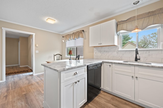 kitchen featuring a sink, a peninsula, white cabinets, decorative backsplash, and light wood-style floors