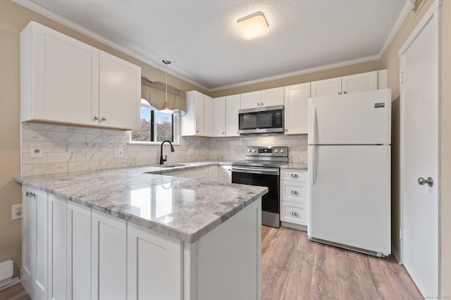 kitchen with appliances with stainless steel finishes, a sink, a peninsula, white cabinets, and crown molding