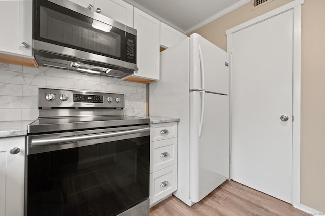 kitchen with stainless steel appliances, ornamental molding, white cabinets, tasteful backsplash, and light wood-style floors
