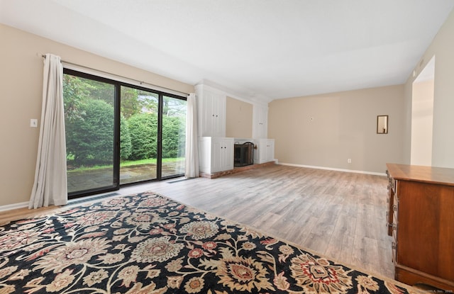unfurnished living room with light wood-type flooring, a fireplace, and baseboards