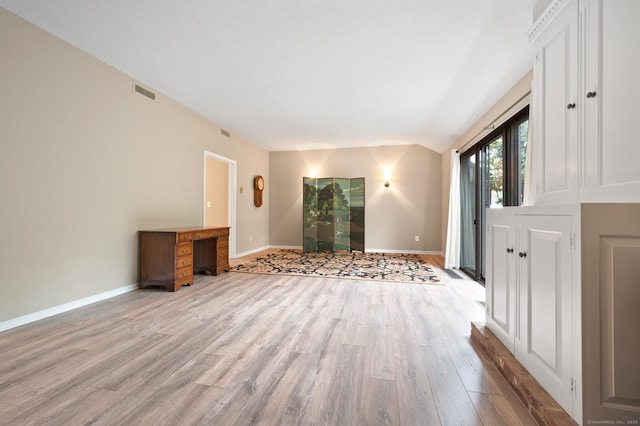 unfurnished living room with light wood-type flooring, baseboards, and lofted ceiling