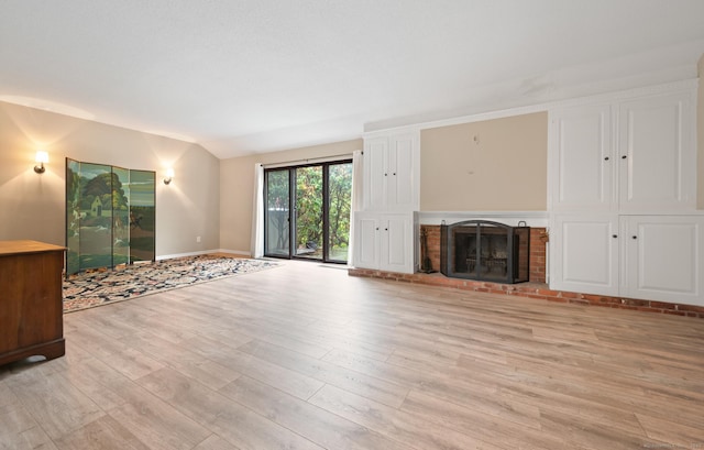 unfurnished living room with light wood-type flooring, a fireplace, vaulted ceiling, and baseboards