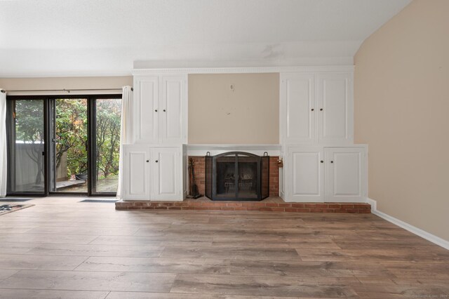 unfurnished living room featuring wood finished floors, a fireplace, and baseboards