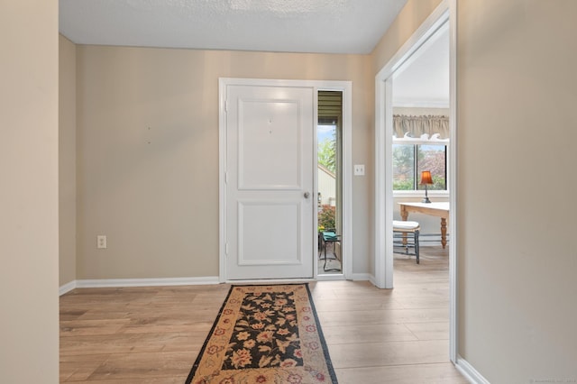 entrance foyer featuring light wood-type flooring, baseboards, and a textured ceiling
