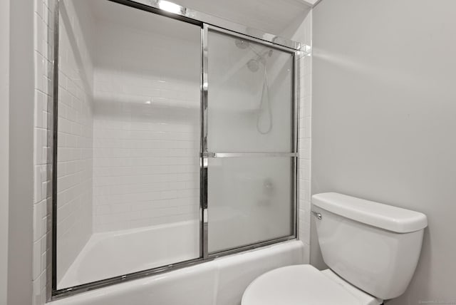 full bath featuring toilet and shower / bath combination with glass door