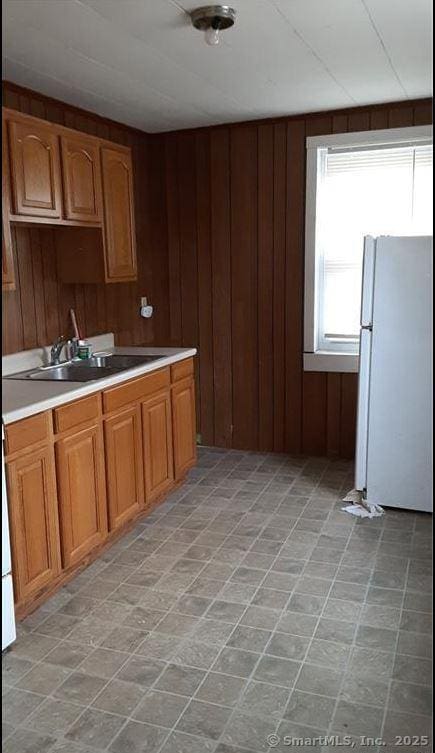 8-12 High St, Putnam, CT 06260 - kitchen featuring freestanding refrigerator, light countertops, wooden walls, and brown cabinets