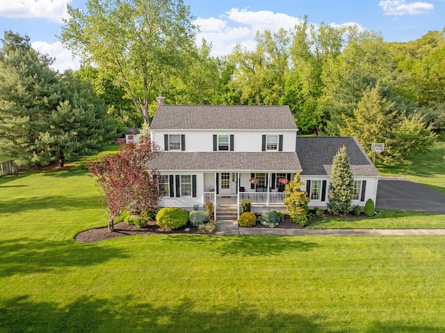 view of front of home featuring covered porch, a front yard, a chimney, and roof with shingles