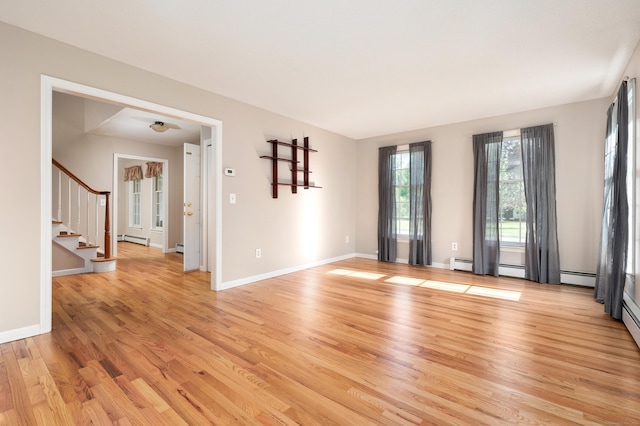 unfurnished room featuring light wood-style floors, a baseboard radiator, stairway, and baseboards