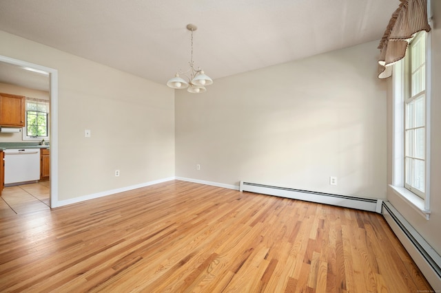 empty room featuring a baseboard radiator, a chandelier, light wood finished floors, and baseboards