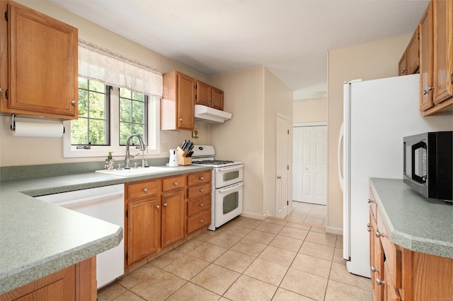 kitchen with white appliances, a sink, under cabinet range hood, light tile patterned flooring, and light countertops