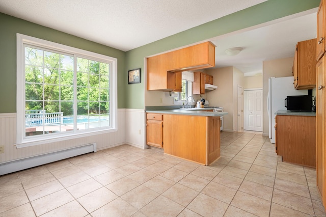 kitchen with a peninsula, a wainscoted wall, light tile patterned floors, under cabinet range hood, and a textured ceiling
