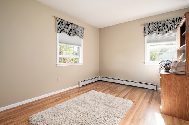 bedroom with light wood-style floors, multiple windows, baseboards, and baseboard heating