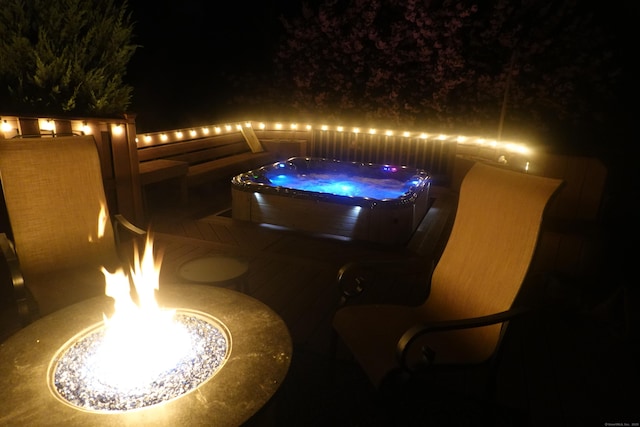 patio at night featuring a hot tub and a fire pit