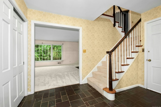 foyer featuring wallpapered walls, baseboards, and stairs