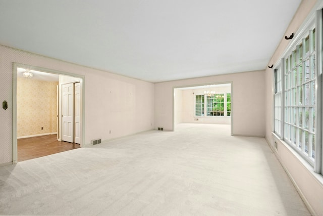 carpeted spare room featuring a chandelier and baseboards