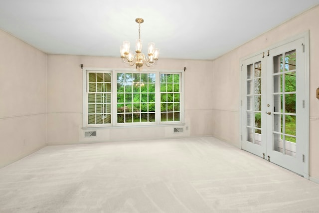 unfurnished dining area with a chandelier, carpet, and french doors