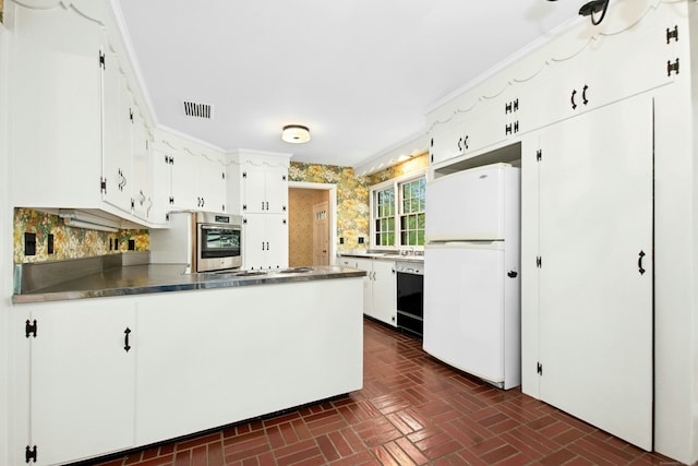 kitchen with freestanding refrigerator, black dishwasher, oven, brick flooring, and a peninsula