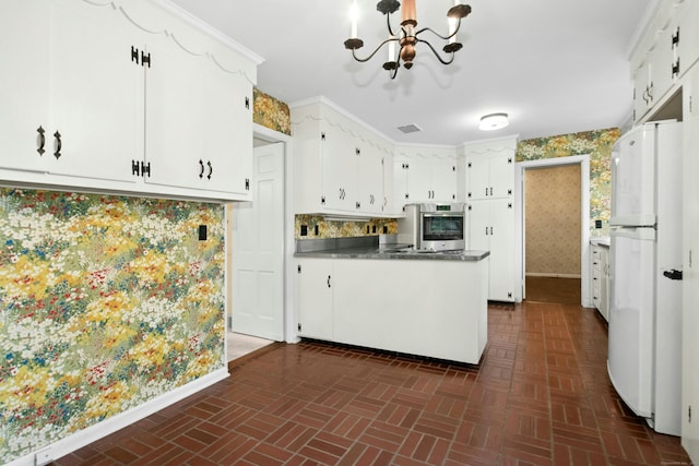 kitchen featuring freestanding refrigerator, brick patterned floors, oven, a peninsula, and a chandelier
