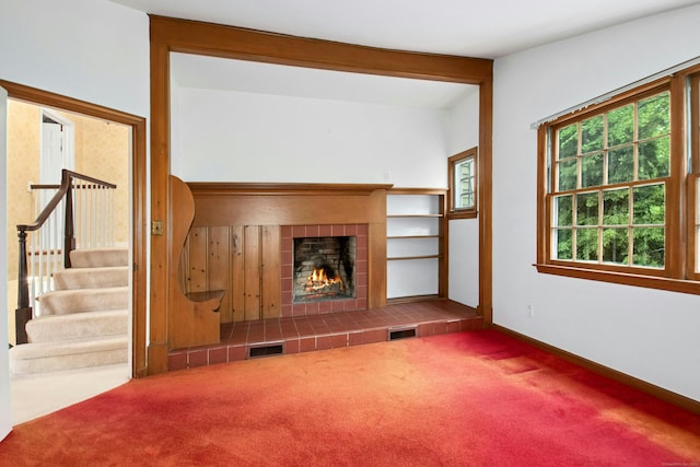 unfurnished living room with carpet floors, a fireplace, baseboards, and stairs