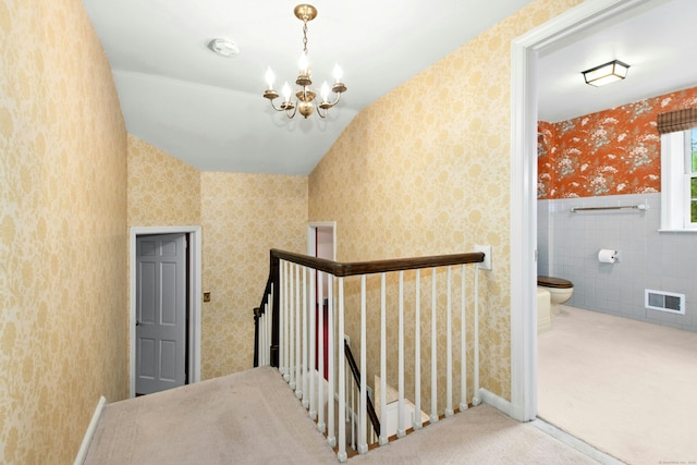 staircase with wallpapered walls, a chandelier, and carpet flooring